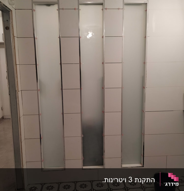 שלושה לוחות זכוכית חלבית מותקנים בקיר אריחים